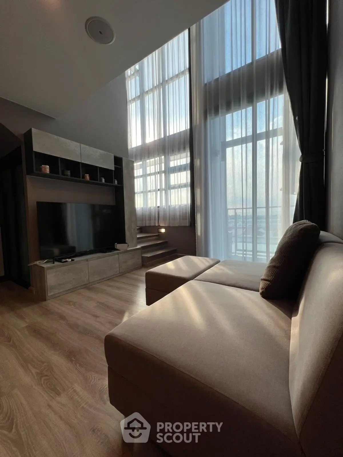 Spacious modern living room with high ceilings and large windows offering ample natural light.