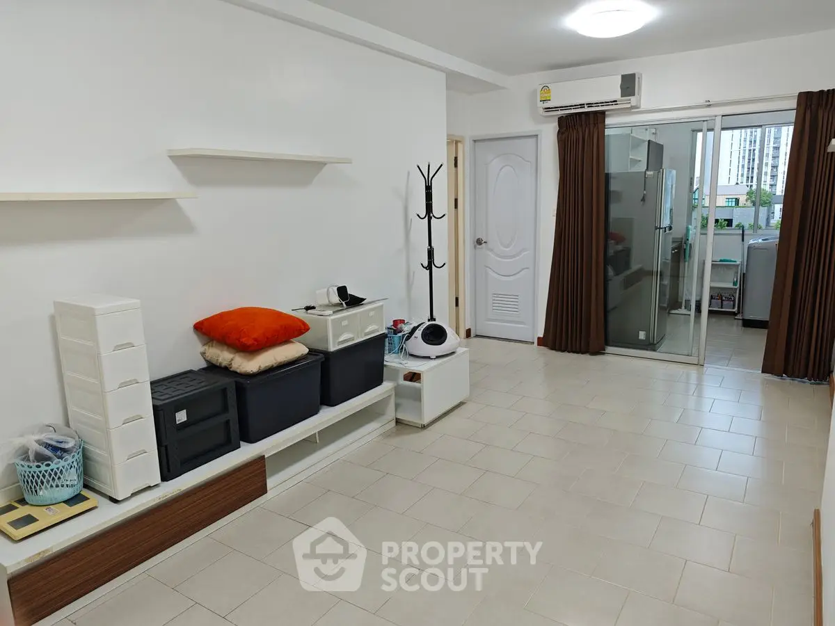 Spacious living room with modern decor and sliding glass doors leading to a bright kitchen area.