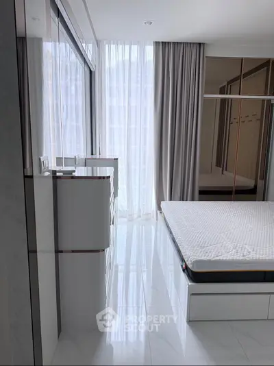 Modern bedroom with large window and sleek furnishings in a stylish apartment.