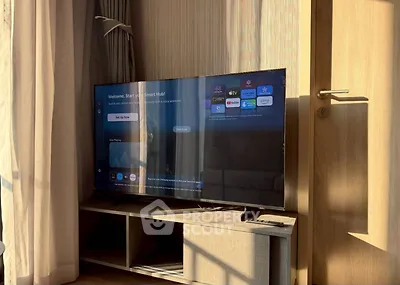 Modern living room with smart TV and sunlight streaming through curtains.