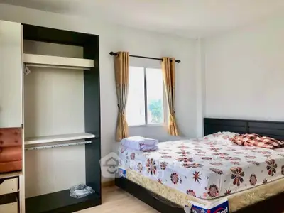 Cozy bedroom with floral bedding and open wardrobe in bright apartment
