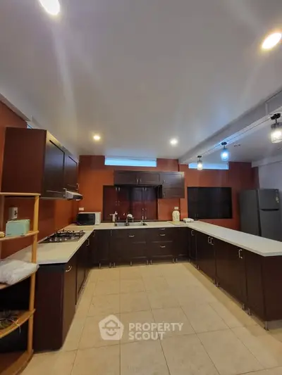 Spacious kitchen with modern cabinetry and gas stove, perfect for culinary enthusiasts.