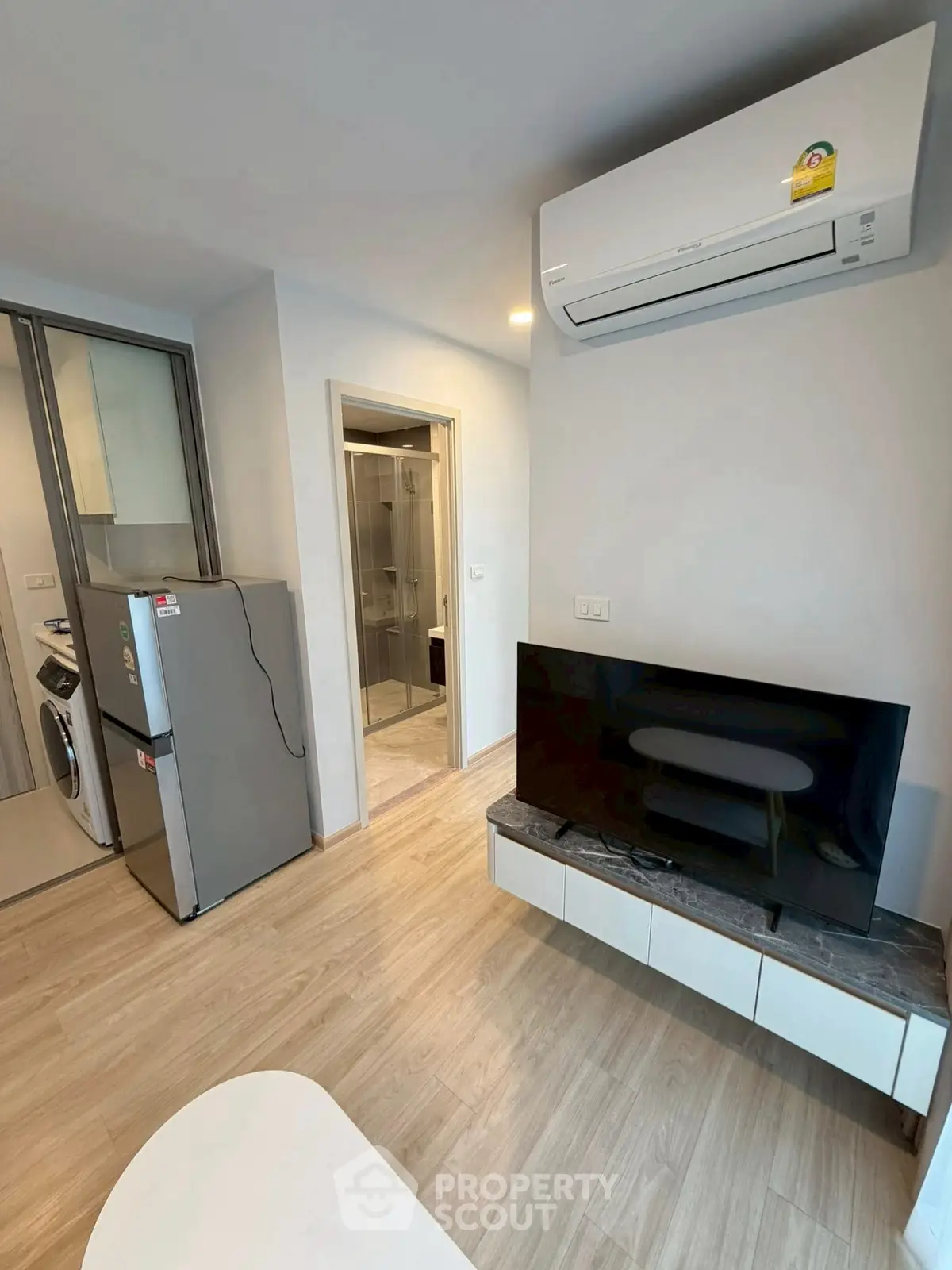Modern apartment interior with air conditioning, TV, and kitchen appliances.