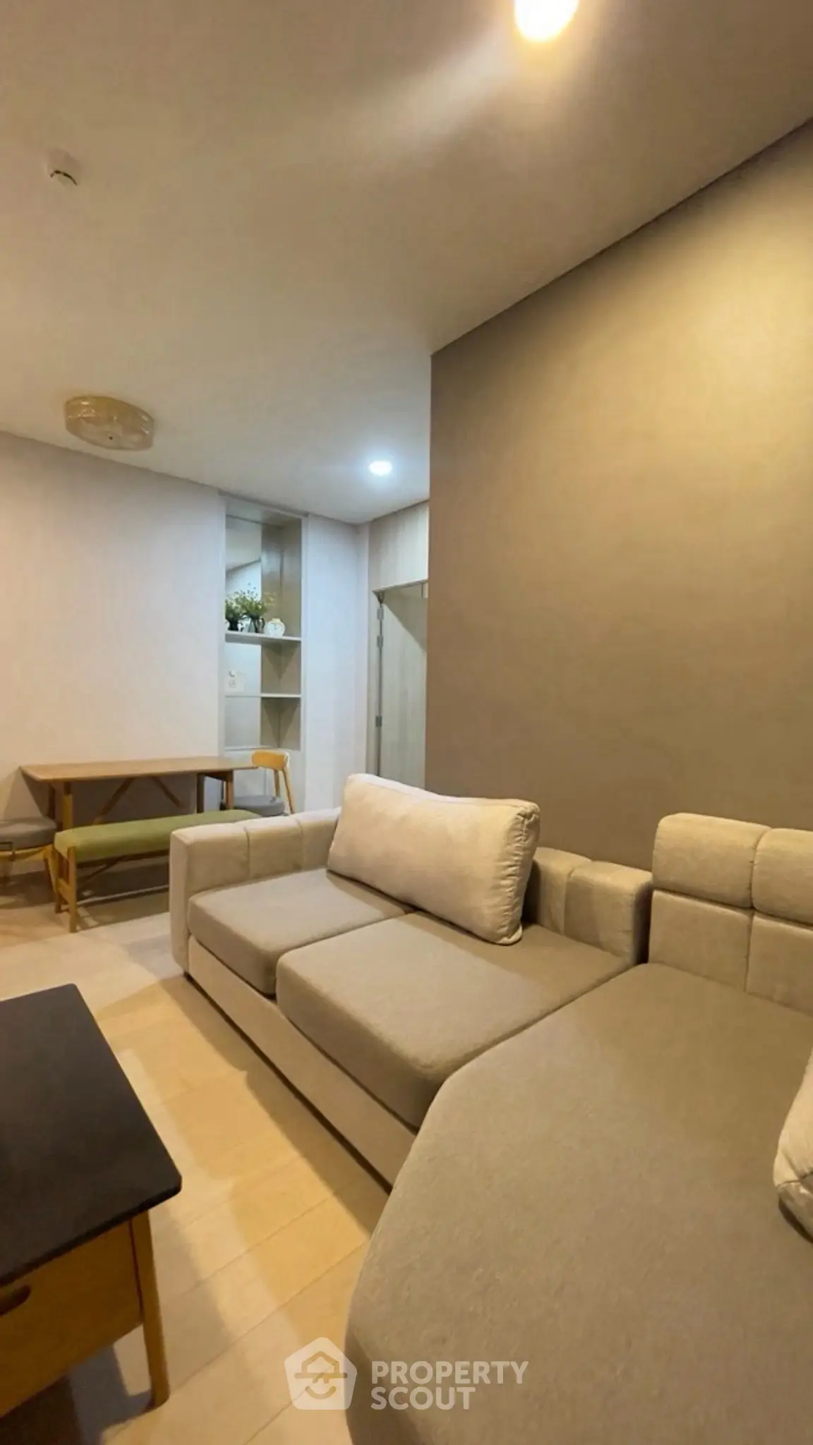 Modern living room with cozy sectional sofa and dining area in open layout apartment.