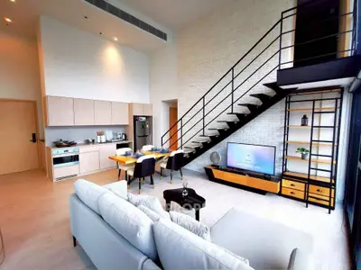 Modern loft apartment with open kitchen and stylish living area featuring a staircase and large windows.