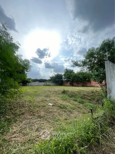 Spacious plot of land with lush greenery and clear sky, perfect for development.