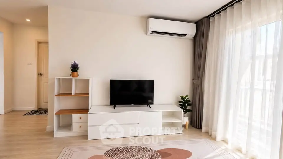 Modern living room with natural light, featuring sleek furniture and air conditioning.