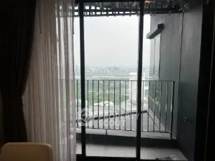 Stunning city view from a modern apartment balcony with glass doors.