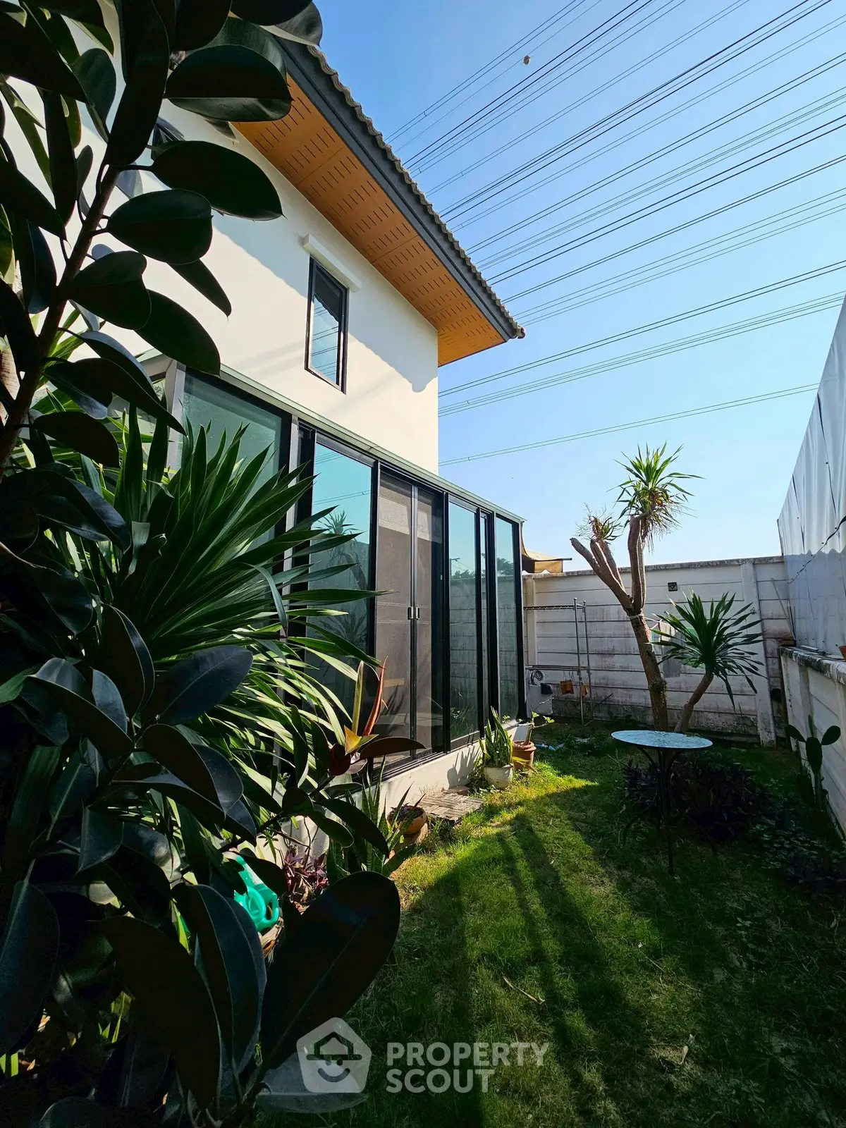 Charming modern home with lush garden and large glass doors, perfect for nature lovers seeking tranquility.