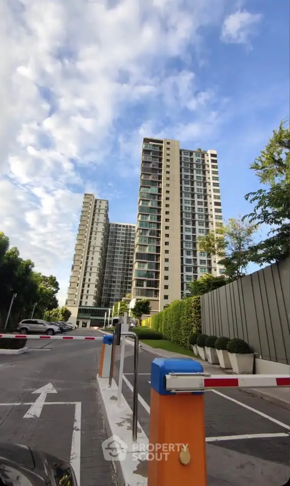 Modern high-rise residential buildings with clear blue sky and lush greenery.