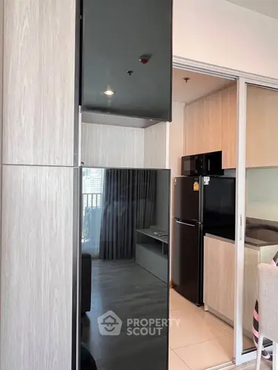 Modern kitchen with sleek black appliances and sliding glass doors in a stylish apartment.