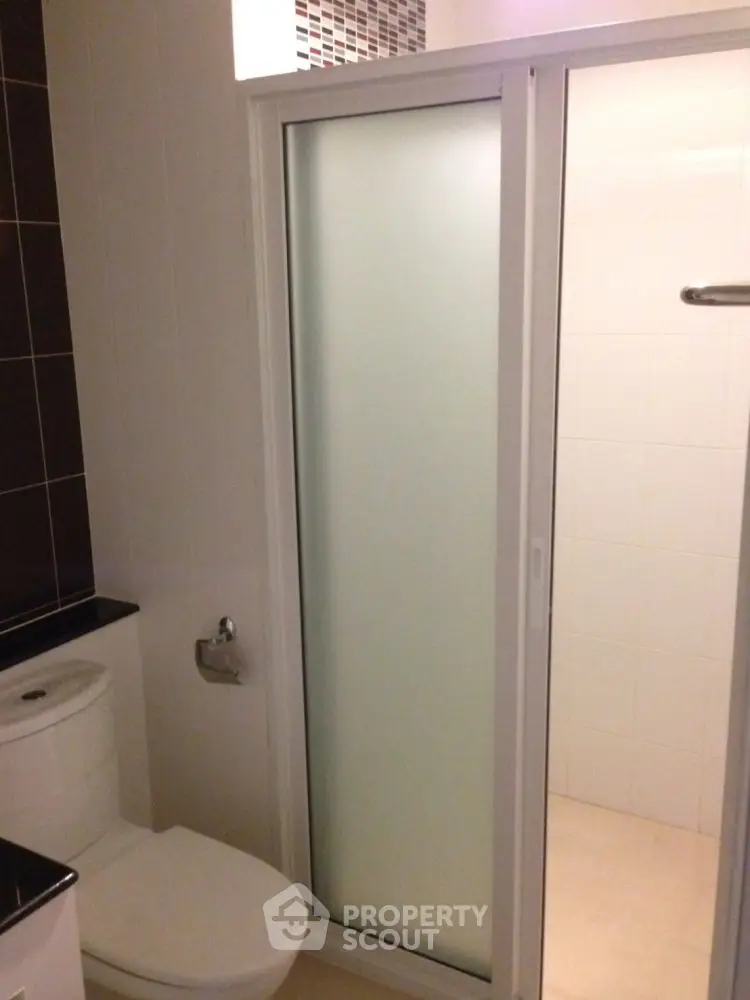Modern bathroom with frosted glass shower door and sleek design.
