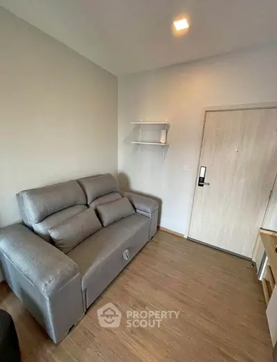 Cozy living room with modern gray sofa and wooden flooring, perfect for relaxation.