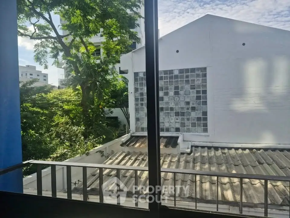 Charming view from a window overlooking lush greenery and neighboring building.