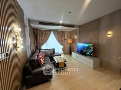 Spacious modern living room with elegant decor and large TV, perfect for relaxation and entertainment.