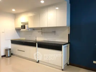 Modern kitchen with sleek white cabinets and built-in microwave, featuring a minimalist design.