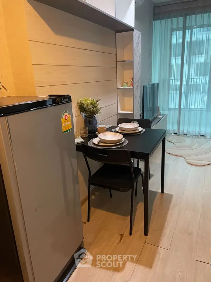 Modern dining area with sleek table, chairs, and compact fridge in stylish apartment.