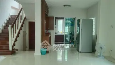 Spacious kitchen with modern appliances and elegant staircase in a bright home interior.