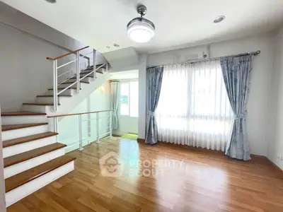 Bright and spacious living room with wooden flooring and elegant staircase
