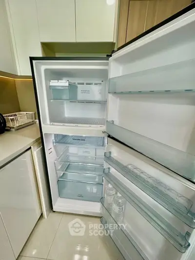 Modern kitchen with open fridge showcasing spacious interior and sleek design.