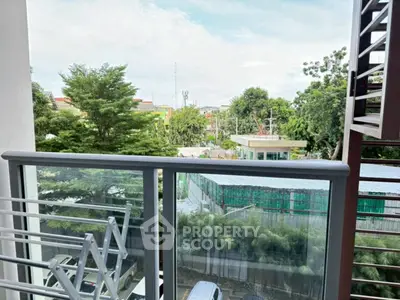 Spacious balcony with lush green view in modern apartment complex.
