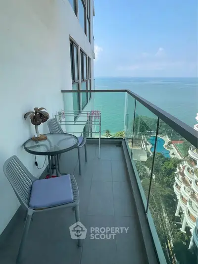 Stunning high-rise balcony with ocean view and cozy seating area.