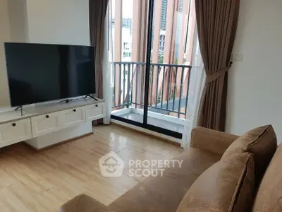 Modern living room with large TV and balcony view in urban apartment.