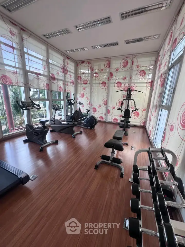 Spacious gym with modern equipment and large windows for natural light.