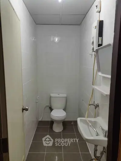 Compact bathroom with white tiles and essential fixtures