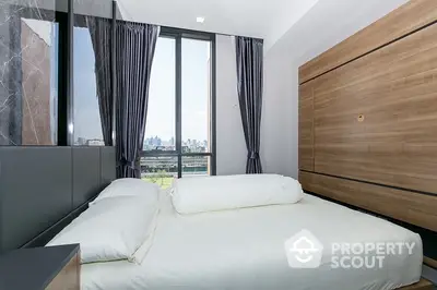 Modern bedroom with large windows offering ample natural light and a stunning city view, featuring a sleek wooden wardrobe and elegant drapery.