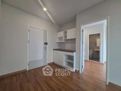 Modern apartment interior with open kitchen and wooden flooring, showcasing minimalist design and ample natural light.