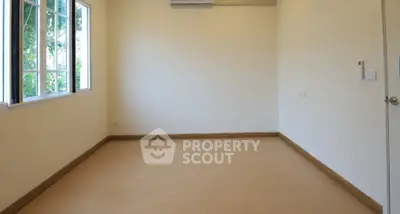 Spacious empty room with large window and air conditioning unit.