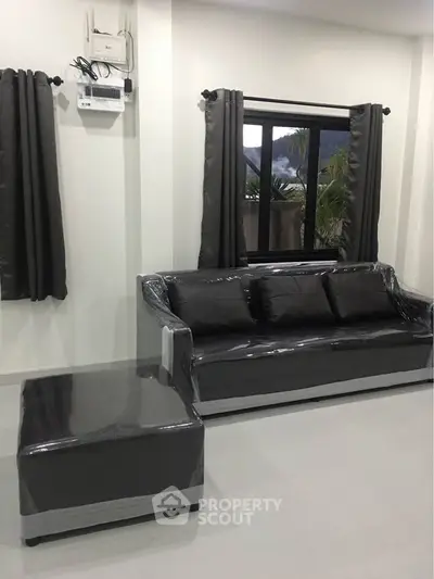 Modern living room with sleek black sofa and window view