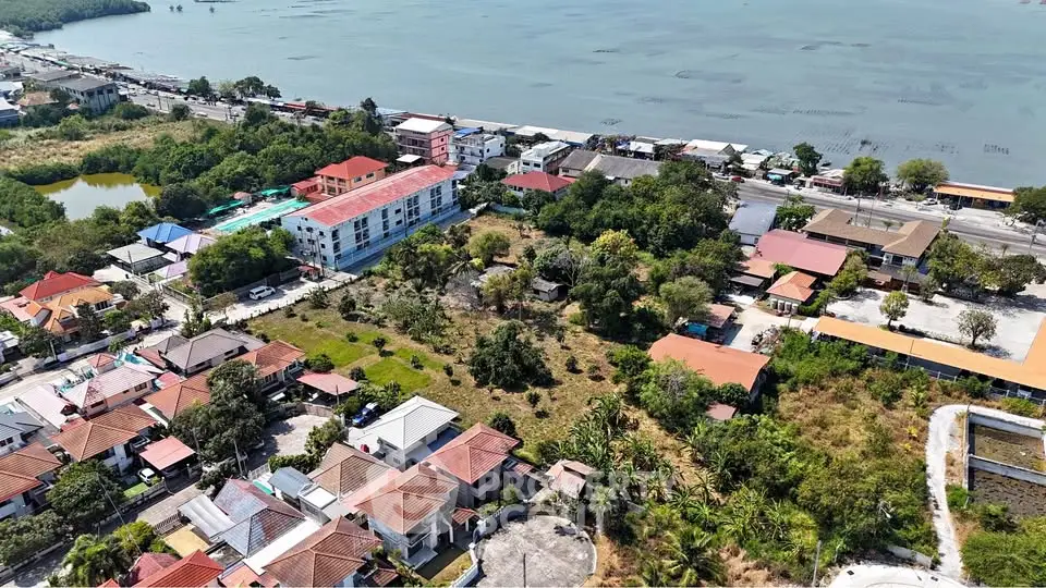 Aerial view of coastal residential area with lush greenery and scenic water backdrop.