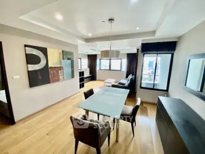 Spacious modern living room with wooden flooring and large windows offering city views.