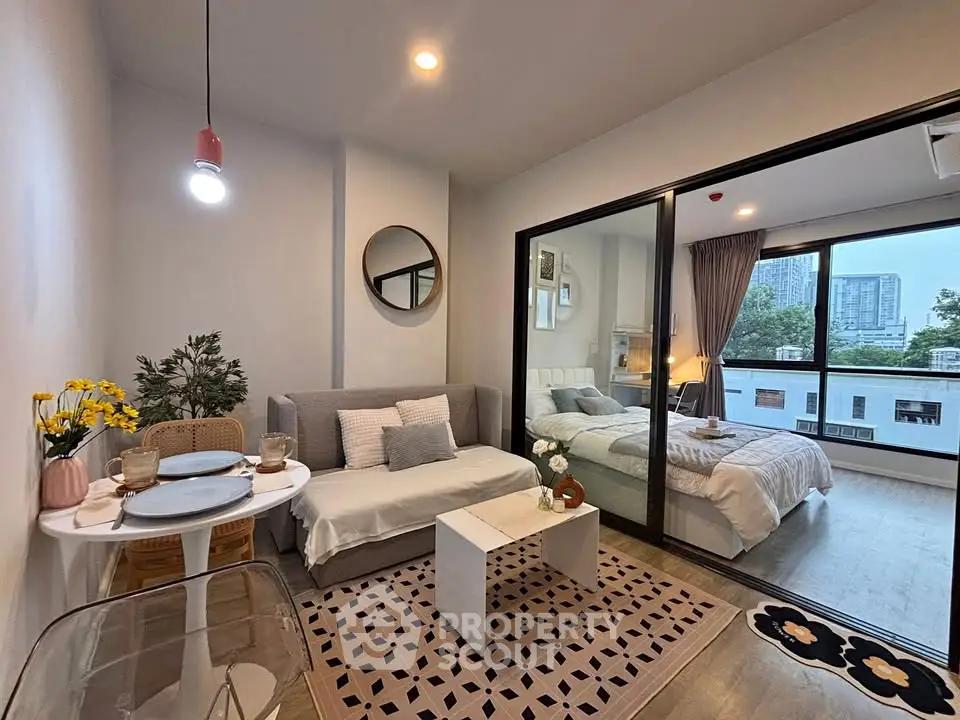 Modern studio apartment with cozy living area and bedroom, featuring large windows and stylish decor.
