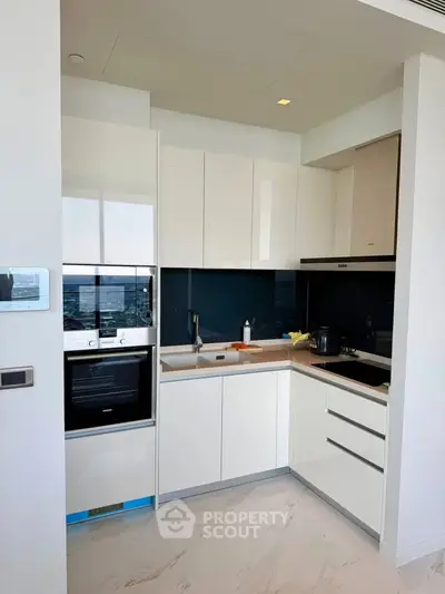 Modern kitchen with sleek white cabinetry and built-in appliances in a contemporary apartment.