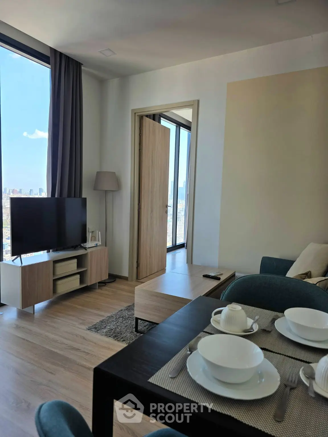 Modern living room with city view, stylish furniture, and dining setup.