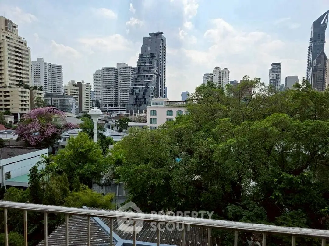 Stunning urban view from a balcony overlooking lush greenery and modern skyscrapers.