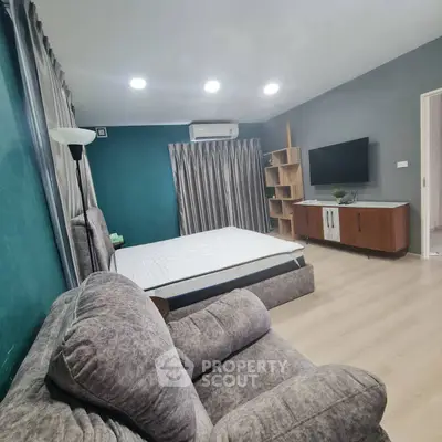 Spacious bedroom with modern decor, featuring a cozy sofa and wall-mounted TV.