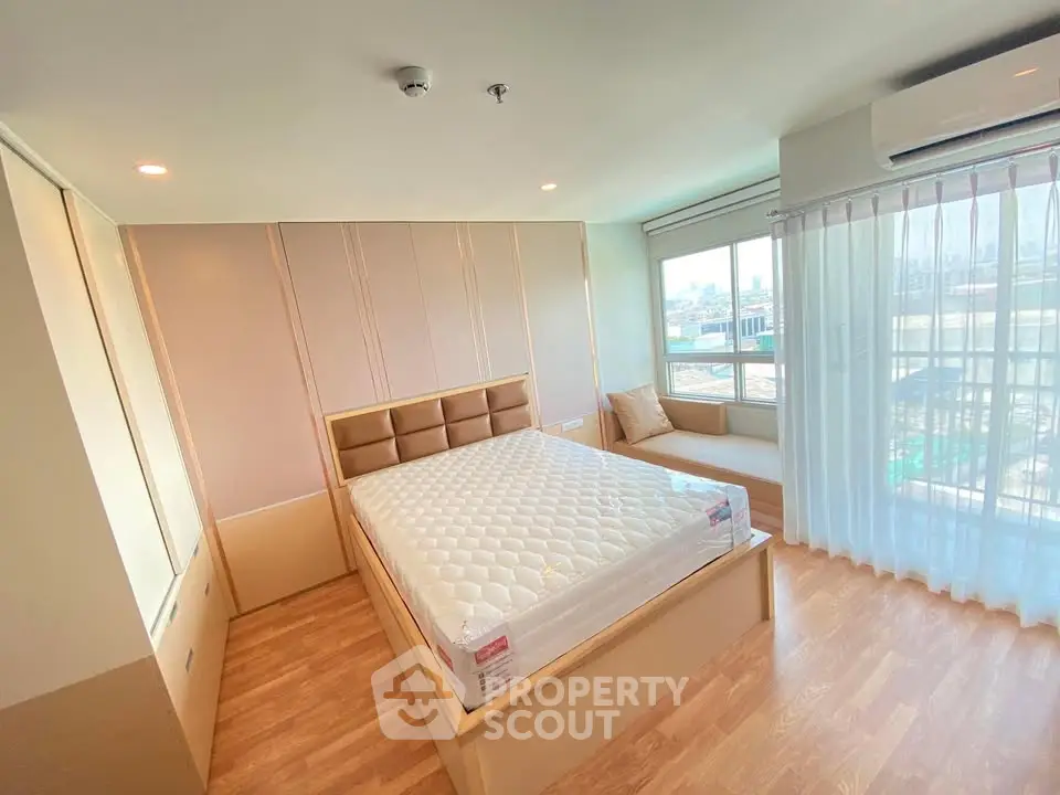 Spacious bedroom with large windows and modern decor in a bright apartment.