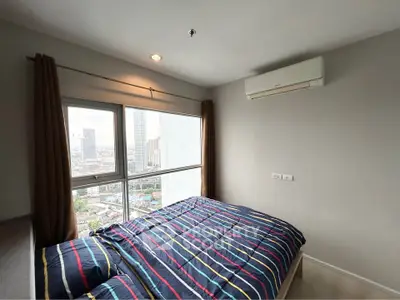 Modern bedroom with city view, featuring large windows and air conditioning.