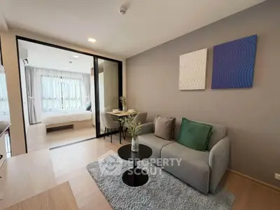 Modern living room with cozy sofa and stylish decor, open layout leading to a bright bedroom with large windows.