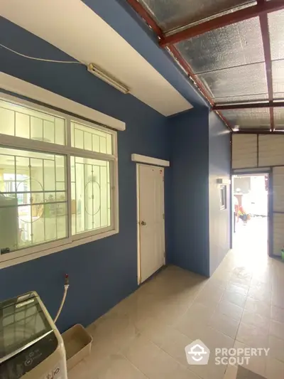 Spacious utility area with washing machine and blue accent wall