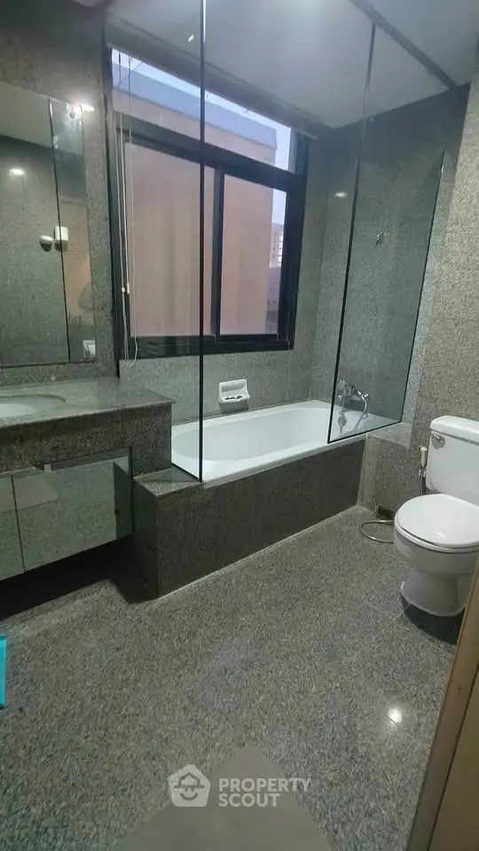 Luxurious bathroom with sleek granite finishes and modern fixtures in upscale apartment.