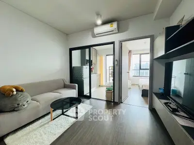 Modern living room with cozy sofa and open view to bedroom and kitchen