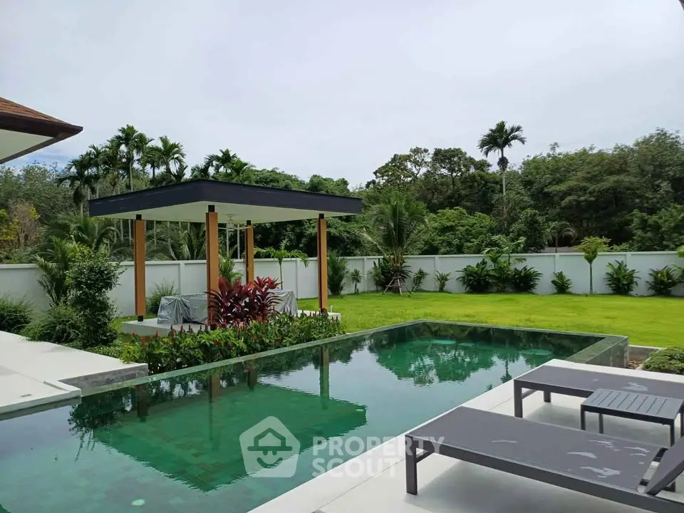 Luxurious outdoor pool area with lush greenery and modern lounge chairs, perfect for relaxation and entertainment.