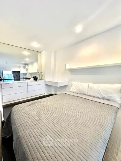 Modern bedroom with sleek design and large mirror reflecting natural light.