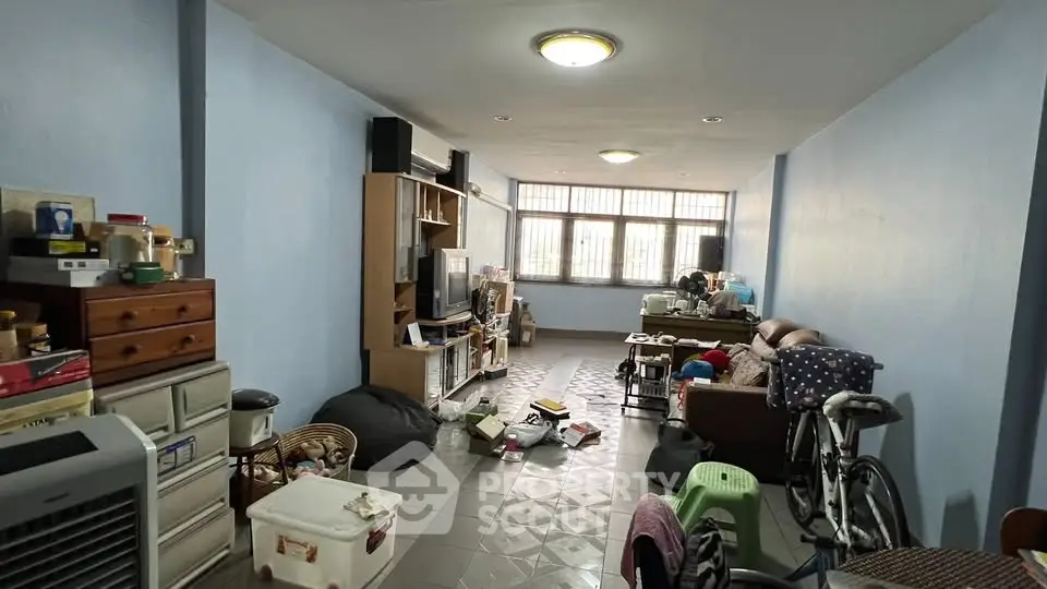 Spacious living room with cluttered interior and natural light