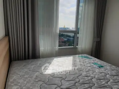 Cozy bedroom with large window offering stunning city view, featuring a comfortable mattress and elegant curtains.